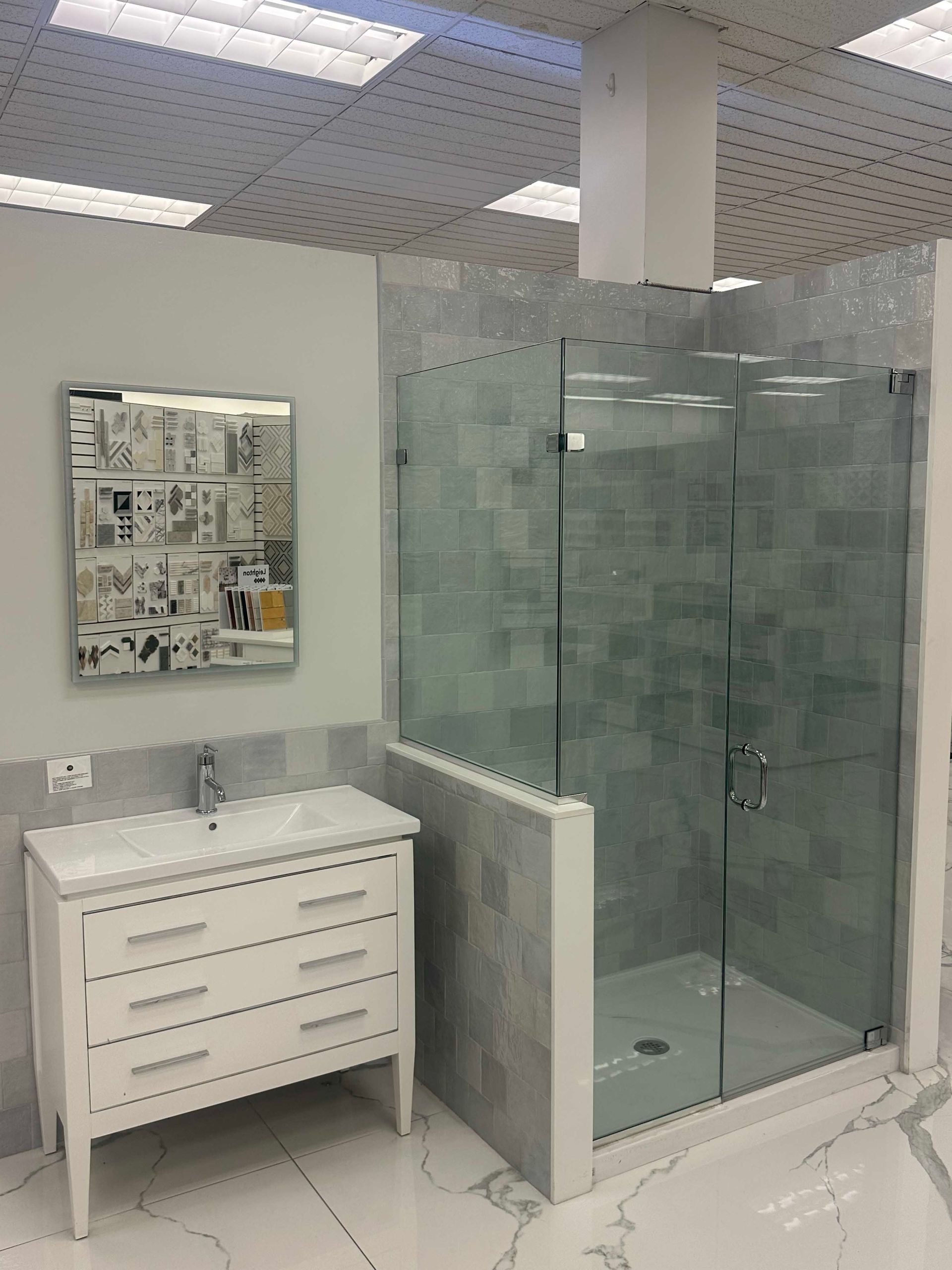 Bathroom with a white vanity, a tiled shower with a glass door, and a decorative mirror.