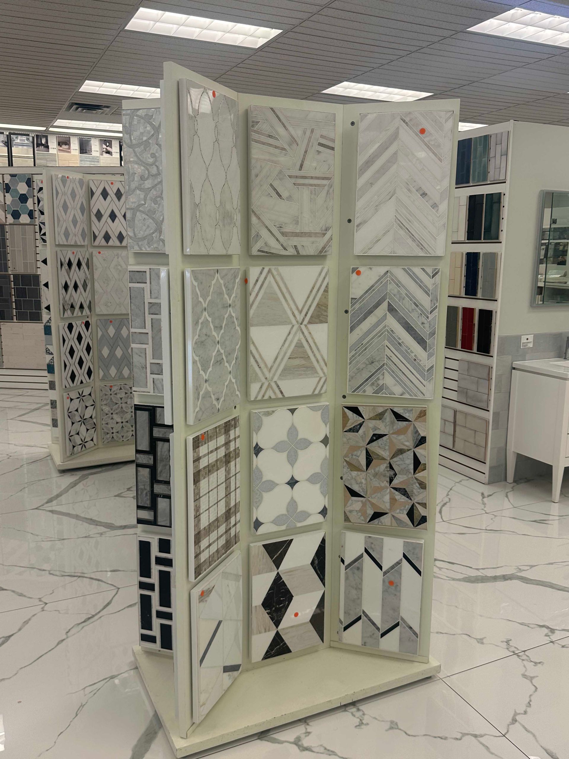 Tile display in a showroom, featuring various patterned tiles in white, gray, and beige.