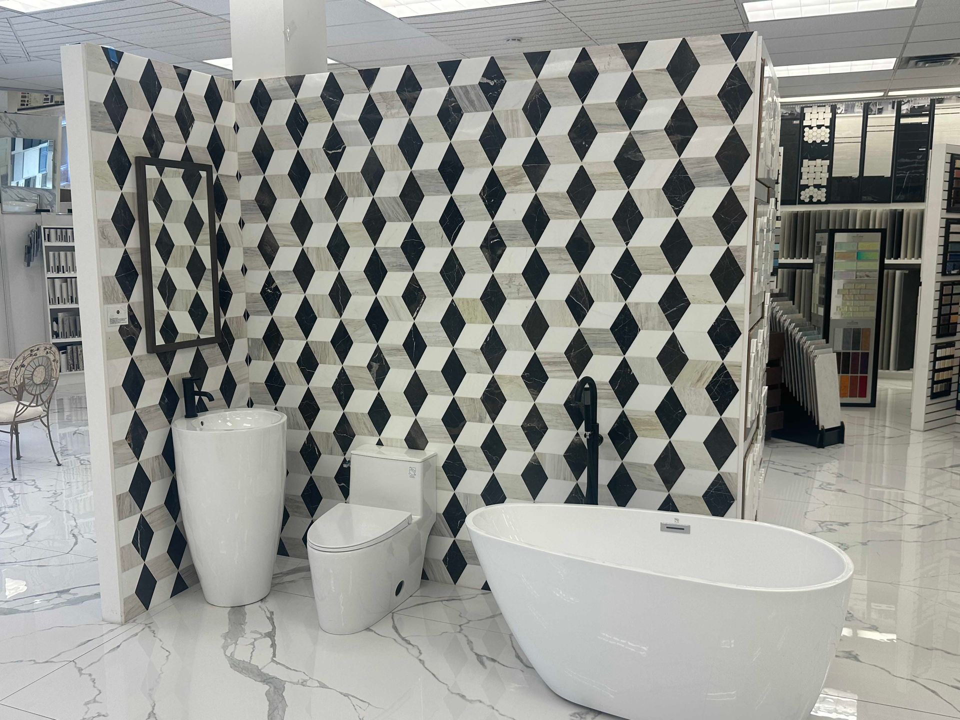 Bathroom display with diamond-patterned tile wall, white fixtures, and a freestanding tub.