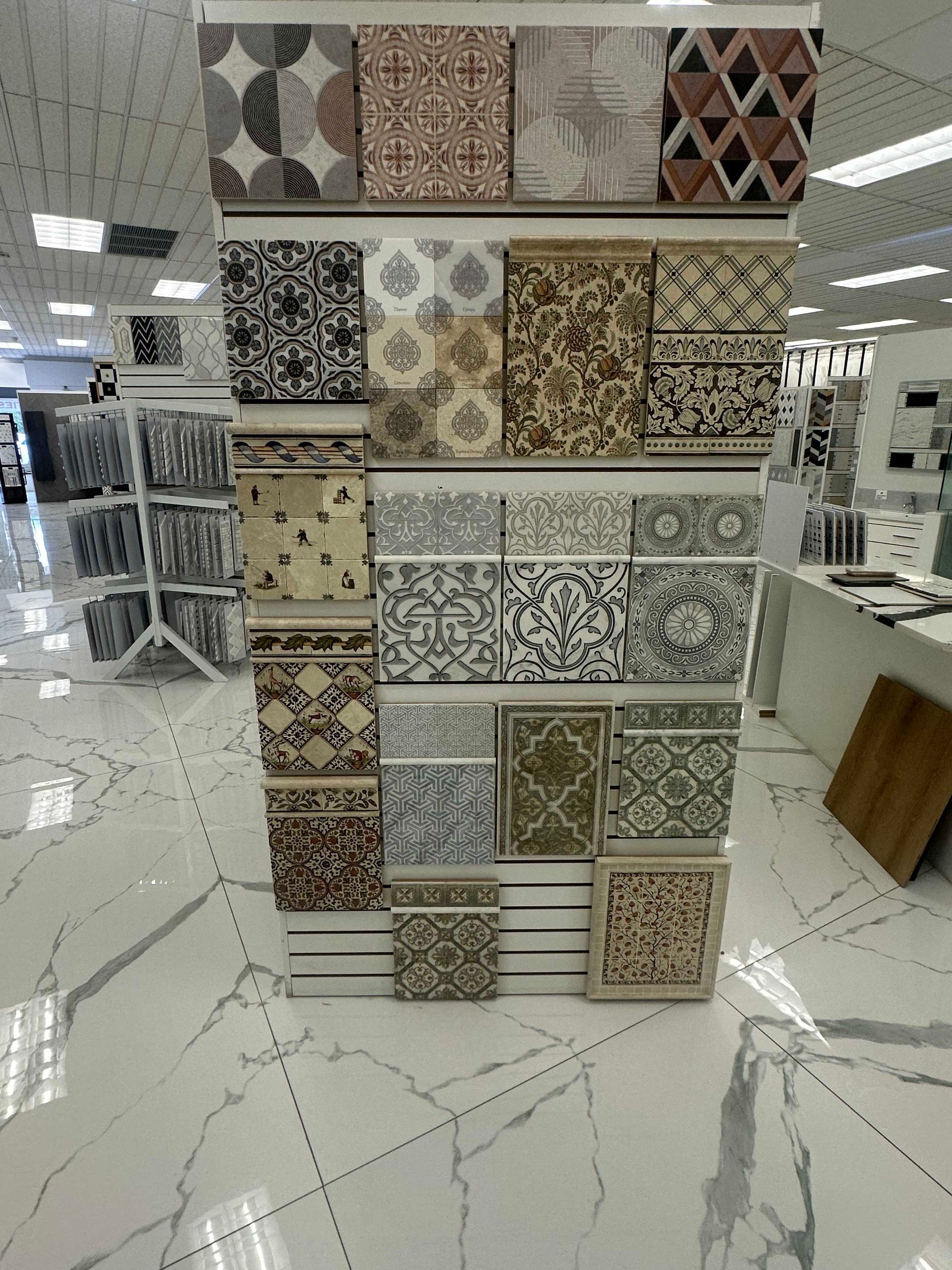 Display stand with various patterned tiles in a showroom, white and marble-look flooring.
