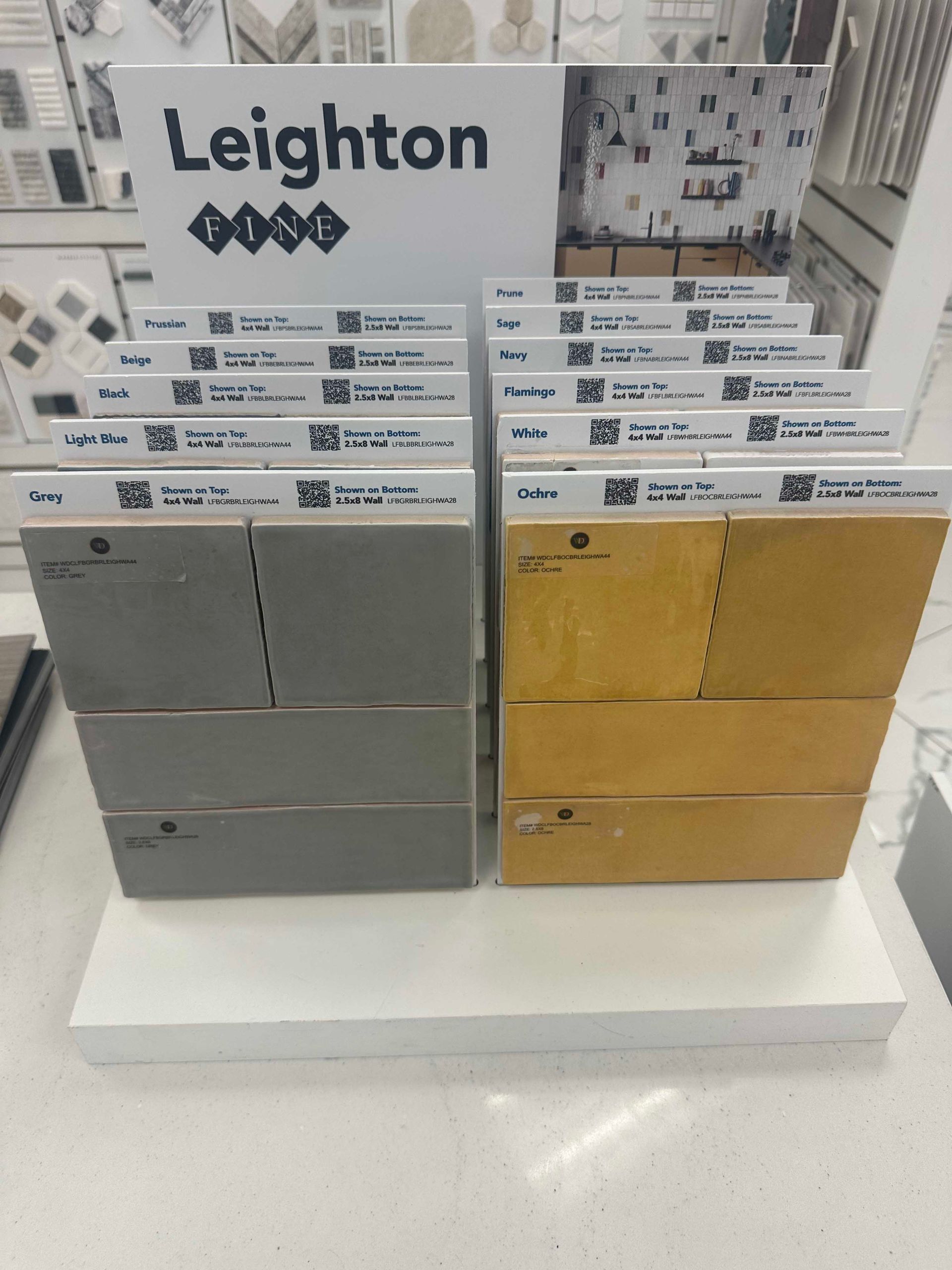 Display of tile samples: grey and gold colors with Leighton logo.