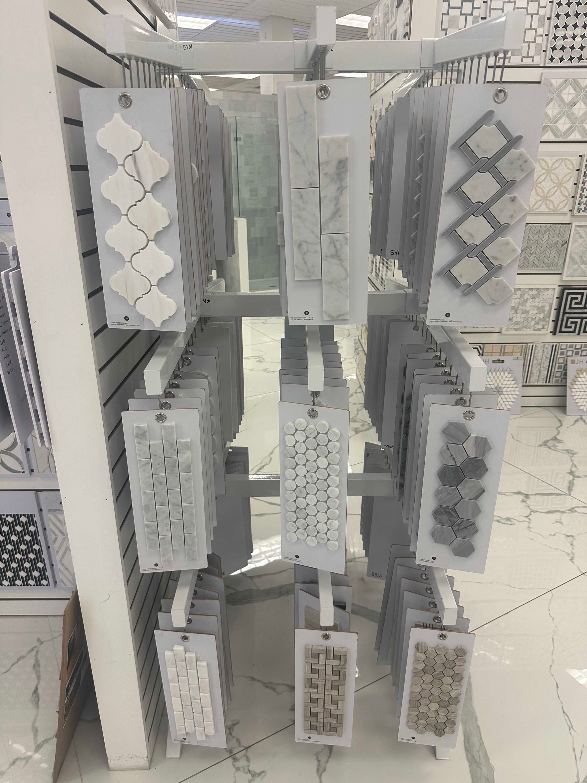 Display rack with various tile samples in a store setting, mostly gray and white.