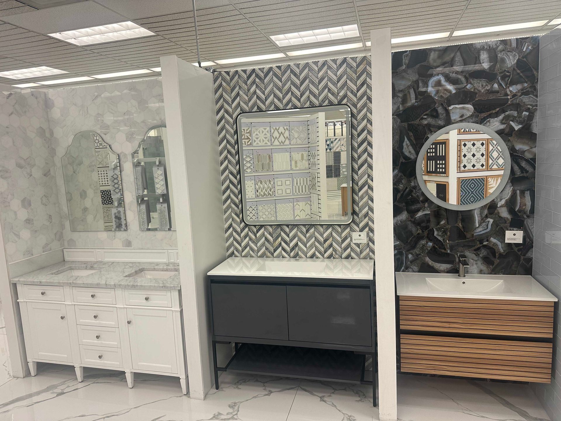 Bathroom vanities on display: white, gray, and wood cabinets, with marble and patterned tile backsplashes.