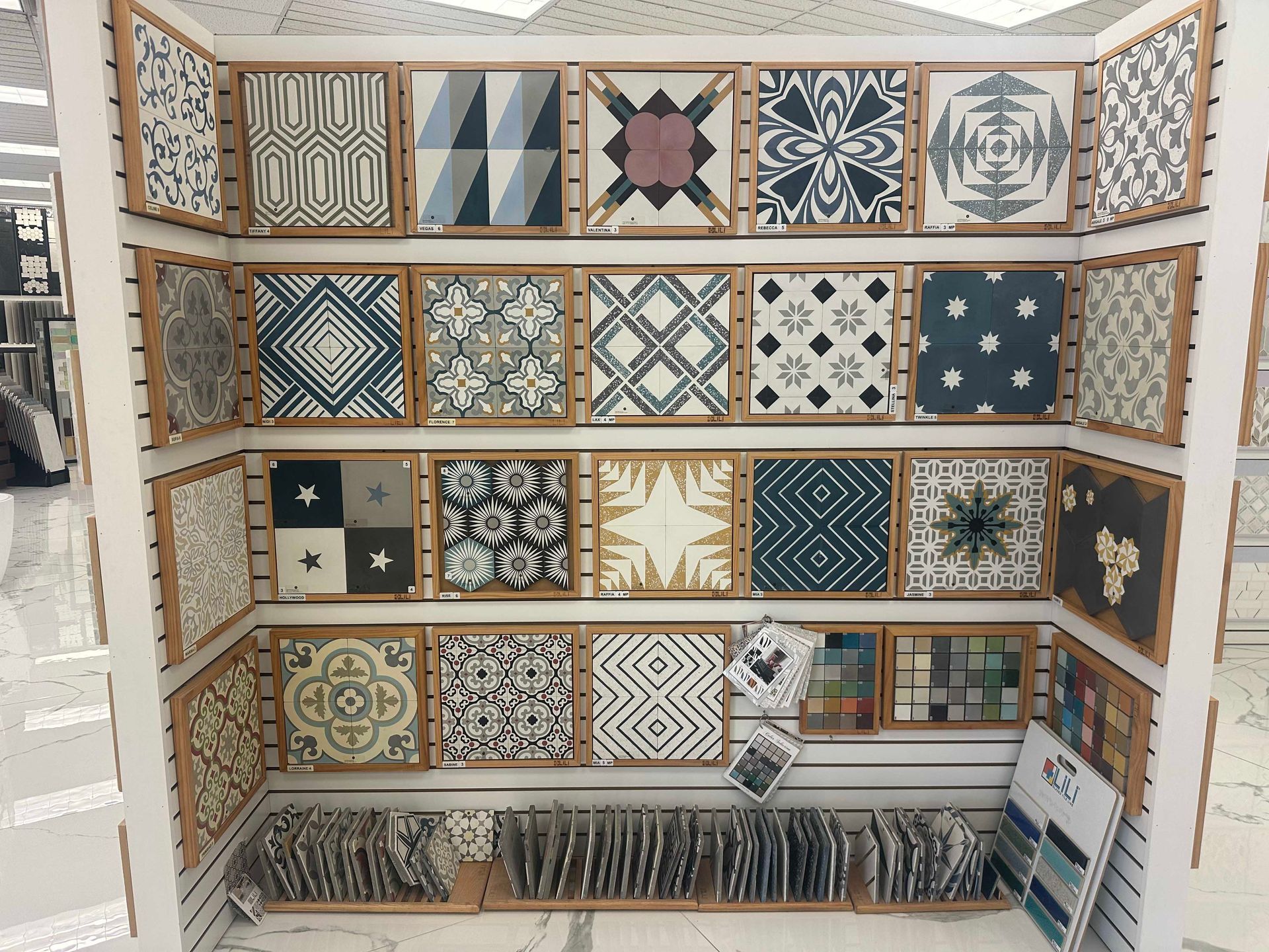 Tile display with various patterned square tiles in wooden frames.