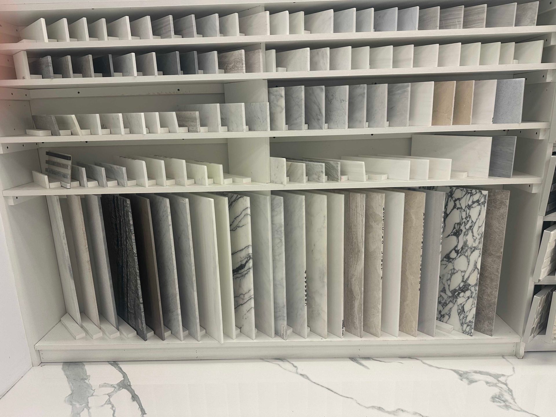 Display of various stone samples arranged on shelves in a showroom.