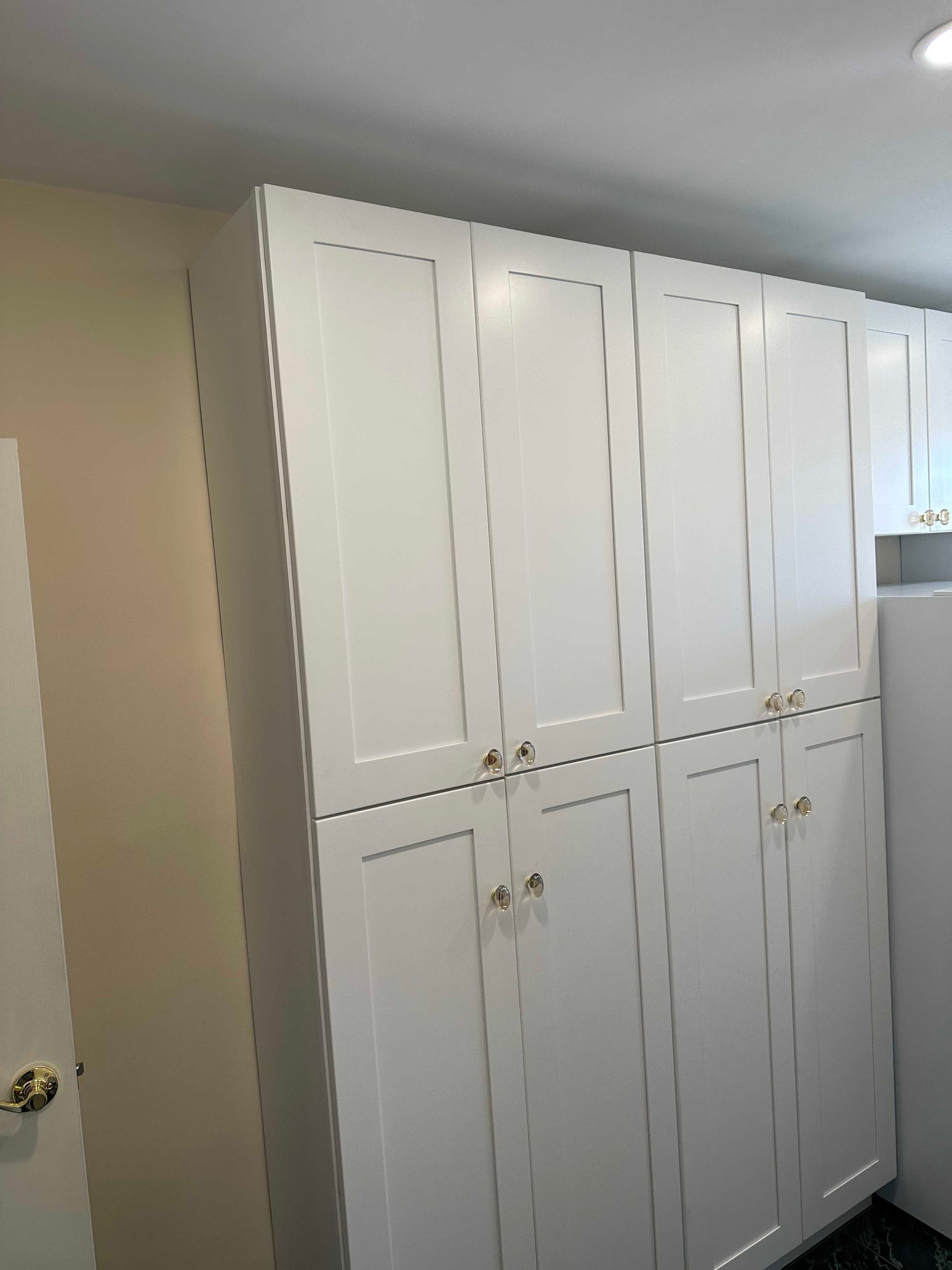 White pantry cabinets with gold handles in a kitchen.
