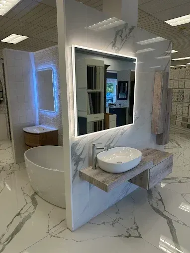 Bathroom display with a backlit mirror, floating vanity, and a soaking tub on marble tile flooring.