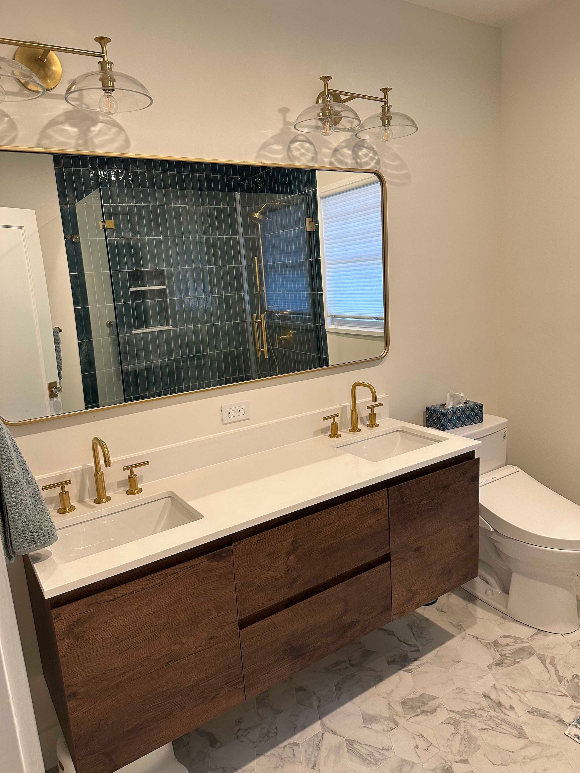 Modern bathroom with floating vanity, gold fixtures, and textured blue tile behind mirror.