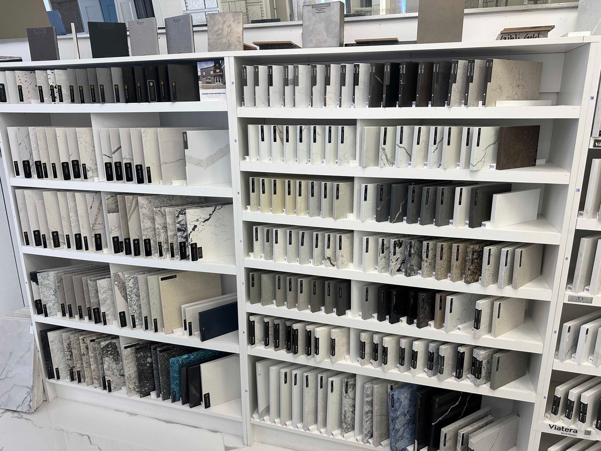 Shelves filled with various countertop samples in a showroom. Many shades of stone, granite, and marble are visible.