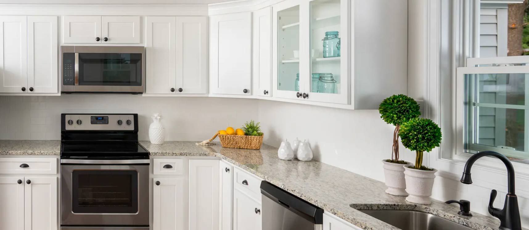White kitchen with granite countertops, stainless steel appliances, and black hardware.