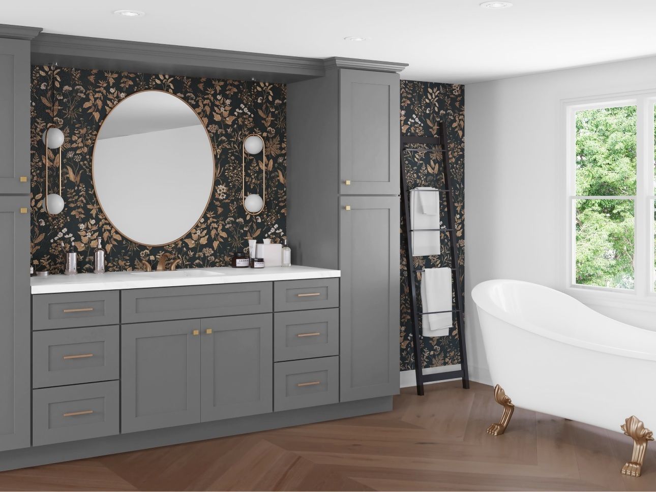 Gray bathroom with oval mirror, vanity, and freestanding tub. Dark patterned wallpaper, wood floor, and window.