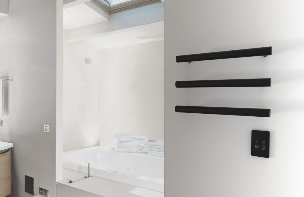 Black towel warmer with three bars and control panel on a white wall in a modern bathroom.