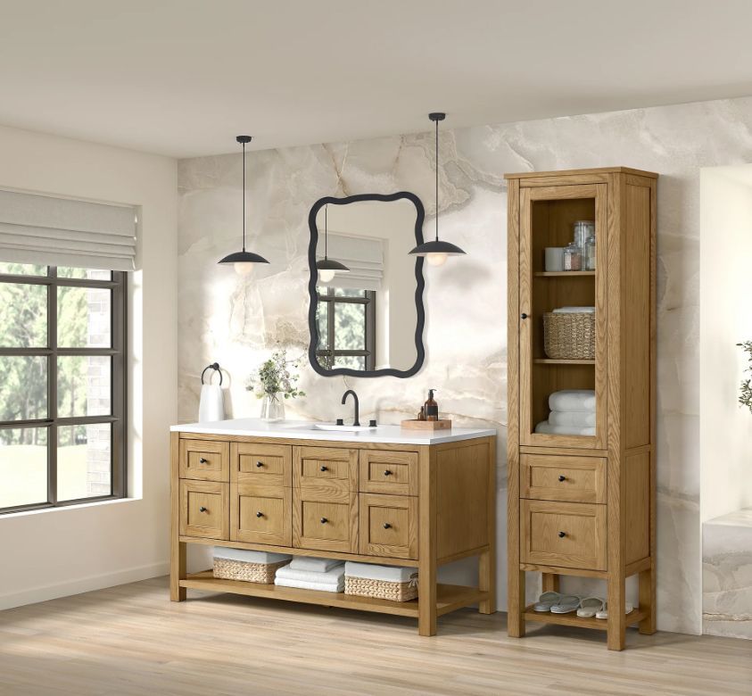 Bathroom with a wooden vanity, cabinet, and a large mirror against a stone wall.