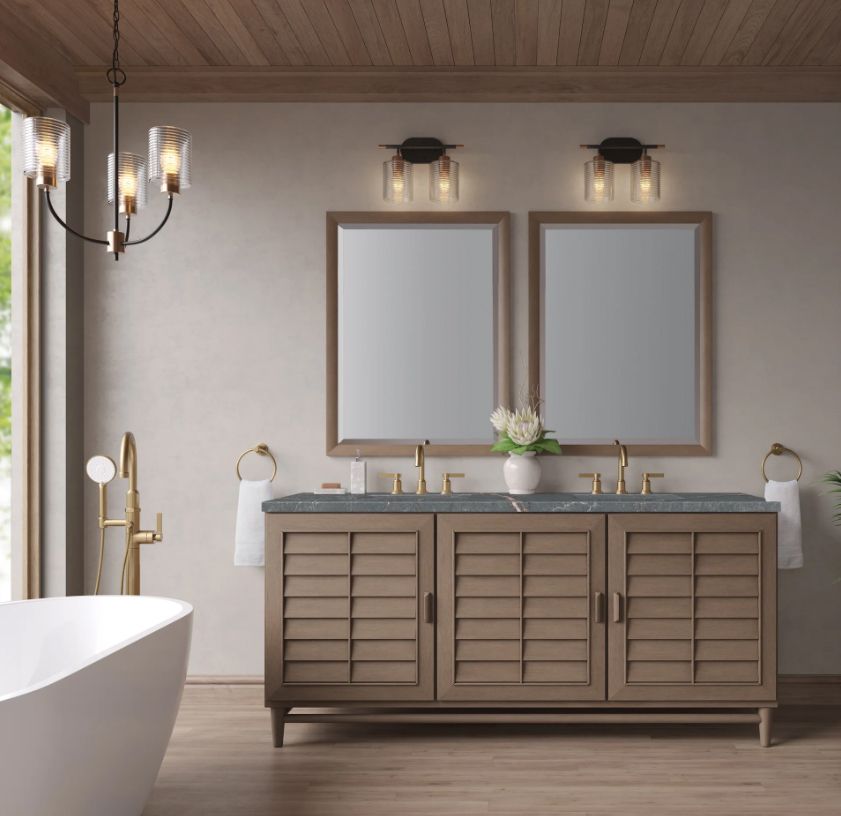 Bathroom with a wooden vanity, mirrors, and sconces; a chandelier hangs overhead.