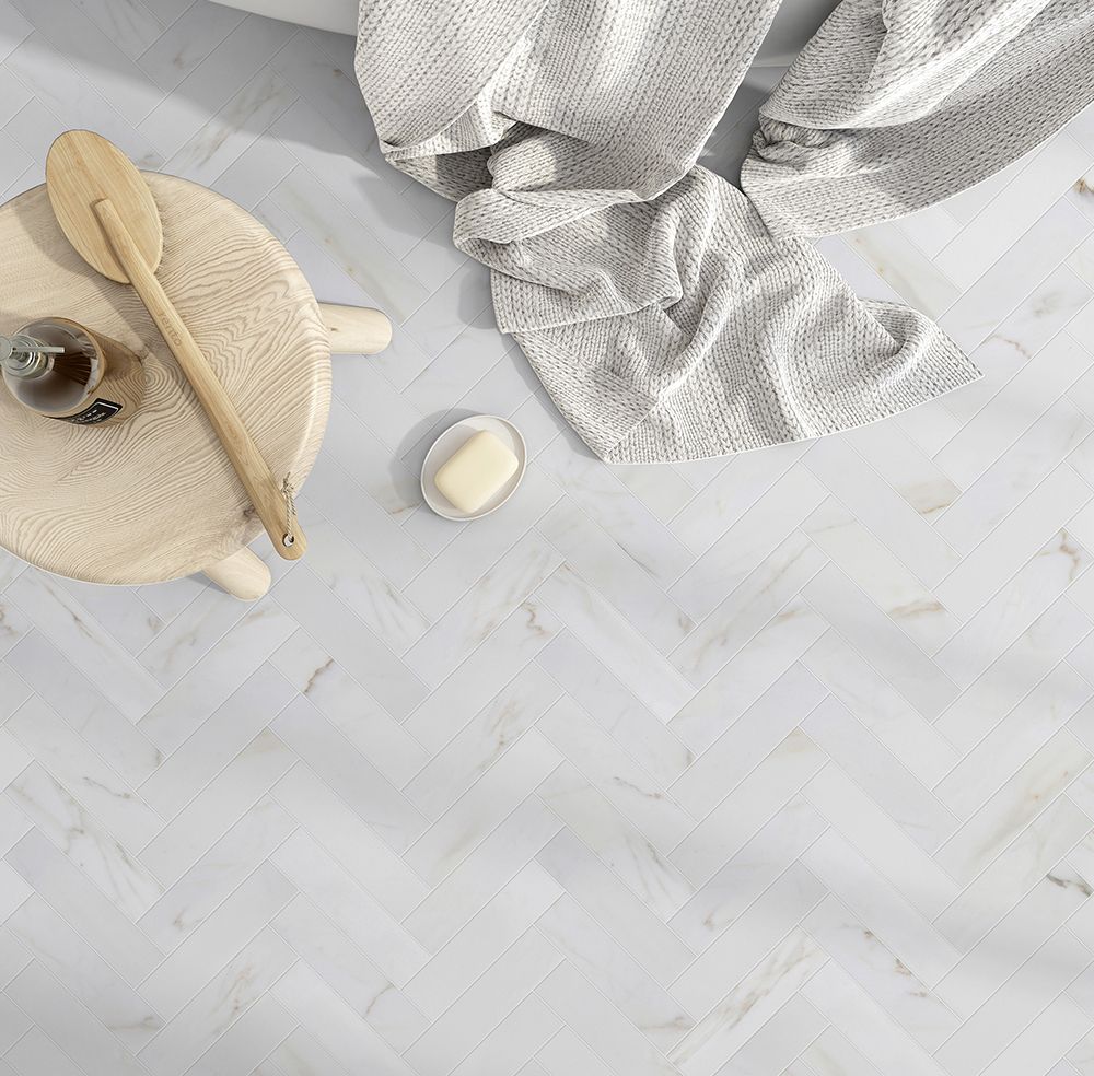 Herringbone patterned white floor with bath items.
