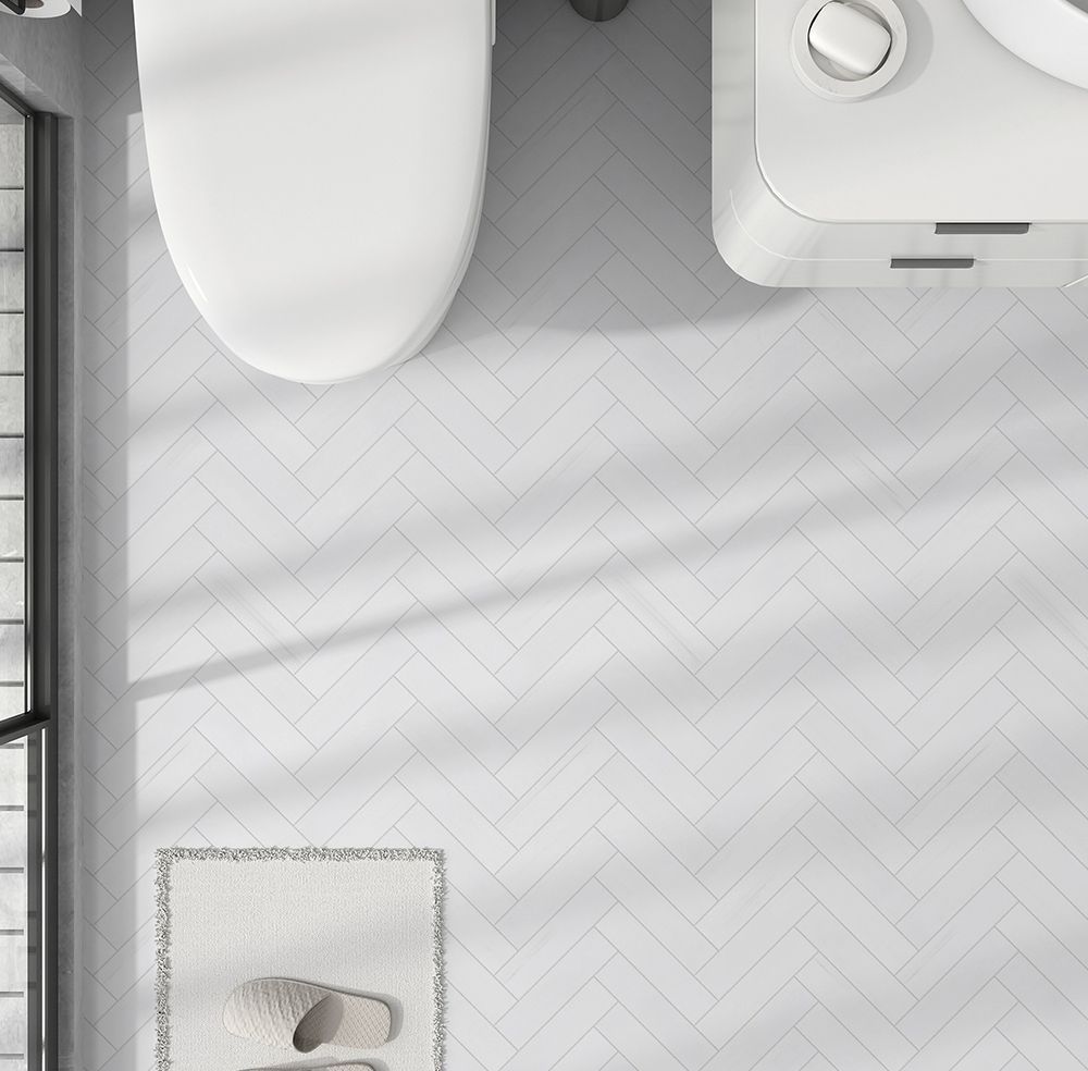 Overhead view of a white bathroom with toilet, washing machine, and herringbone tile floor.