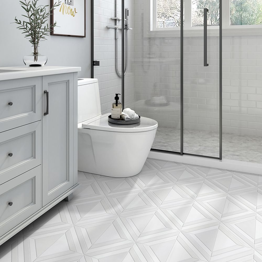 Bathroom with white vanity, toilet, and glass shower. Geometric patterned white floor tiles.