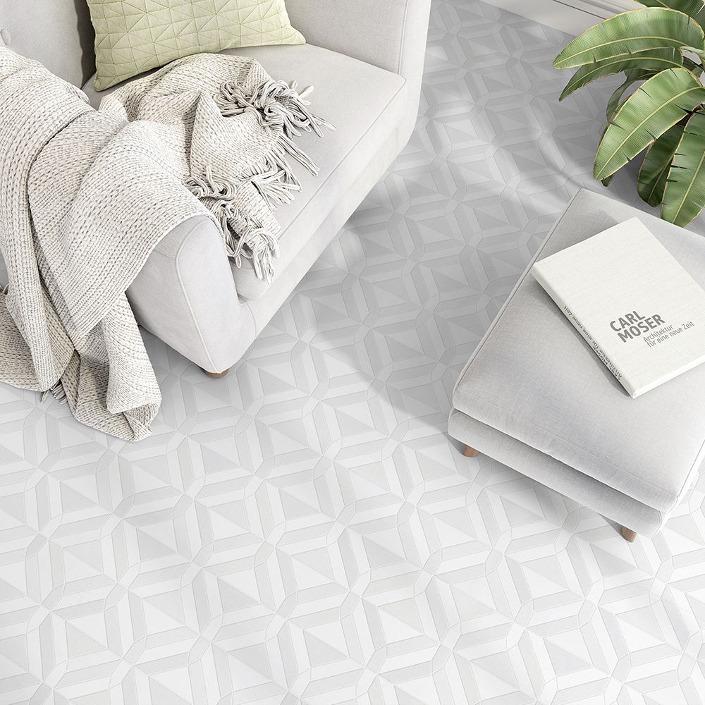 Living room with patterned floor, armchair, ottoman, blanket, pillow, and book.
