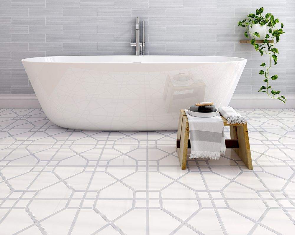 Bathroom with white freestanding tub, patterned tile floor, and a wooden stool with towels.