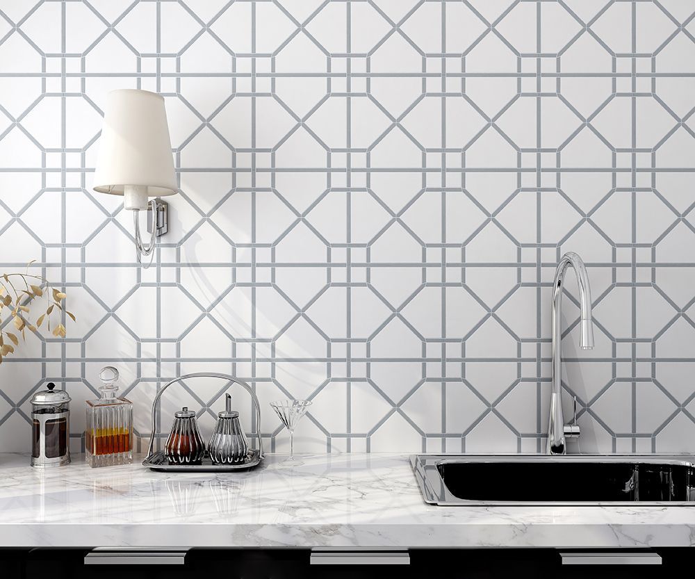 White backsplash with gray geometric pattern behind a sink, countertop, and kitchen accessories.