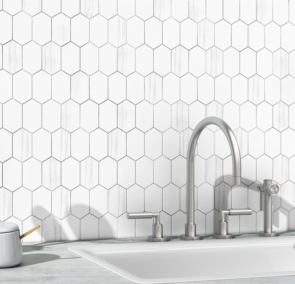 White elongated hexagon tile backsplash with a stainless steel faucet and white sink.