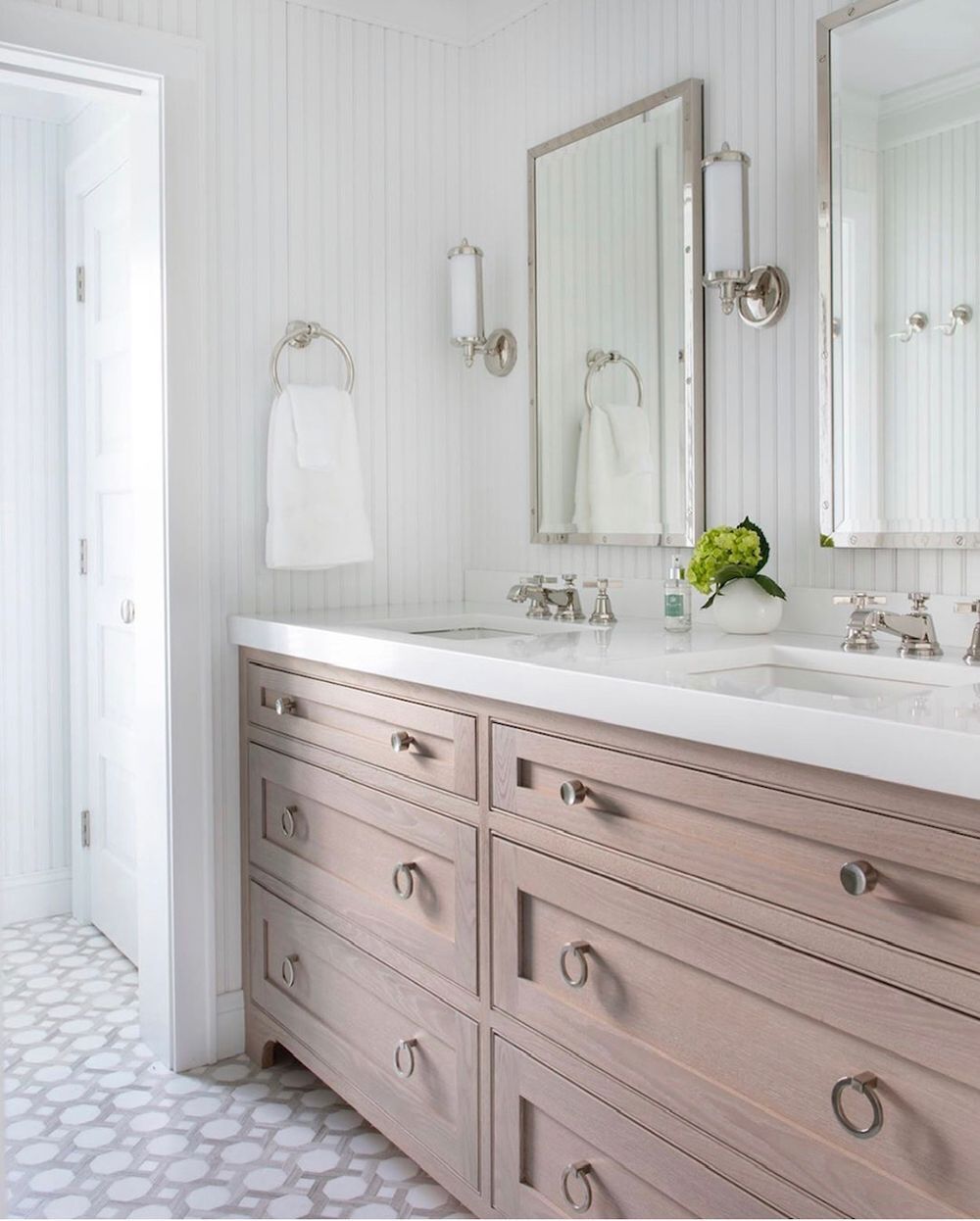 Bathroom with a light brown double vanity, white walls, two mirrors, and a white countertop.