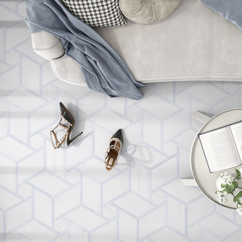White geometric tile floor with sofa, shoes, and small table with book and flowers.