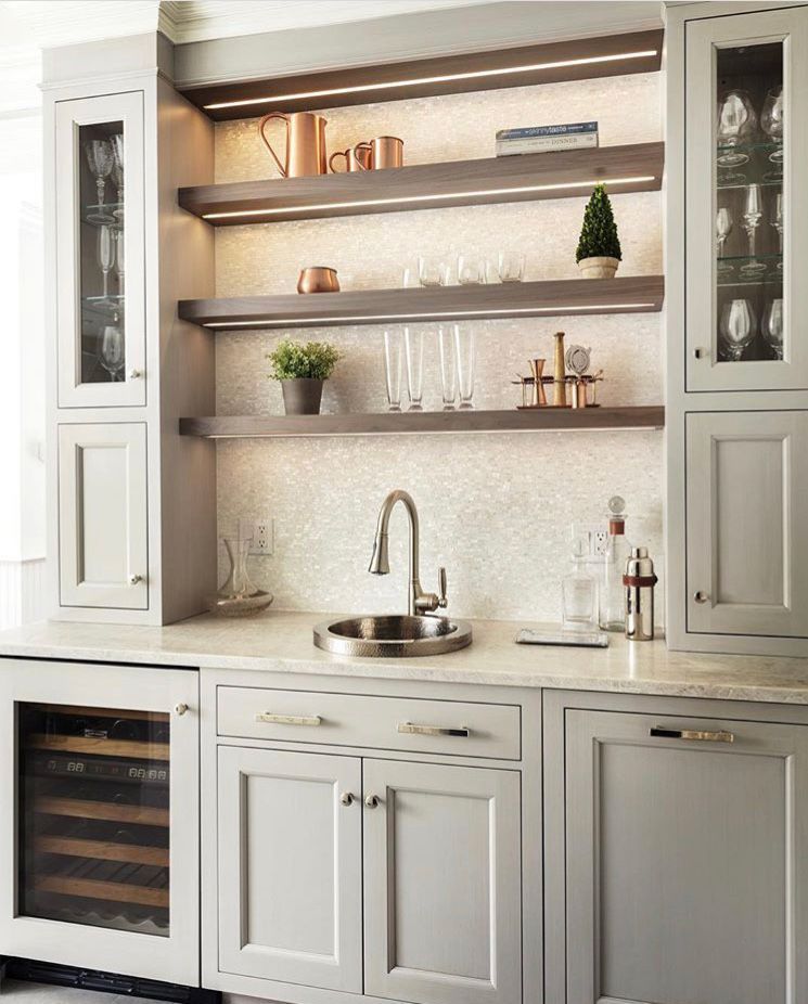 Gray home bar with open shelving, sink, wine fridge, and glassware.