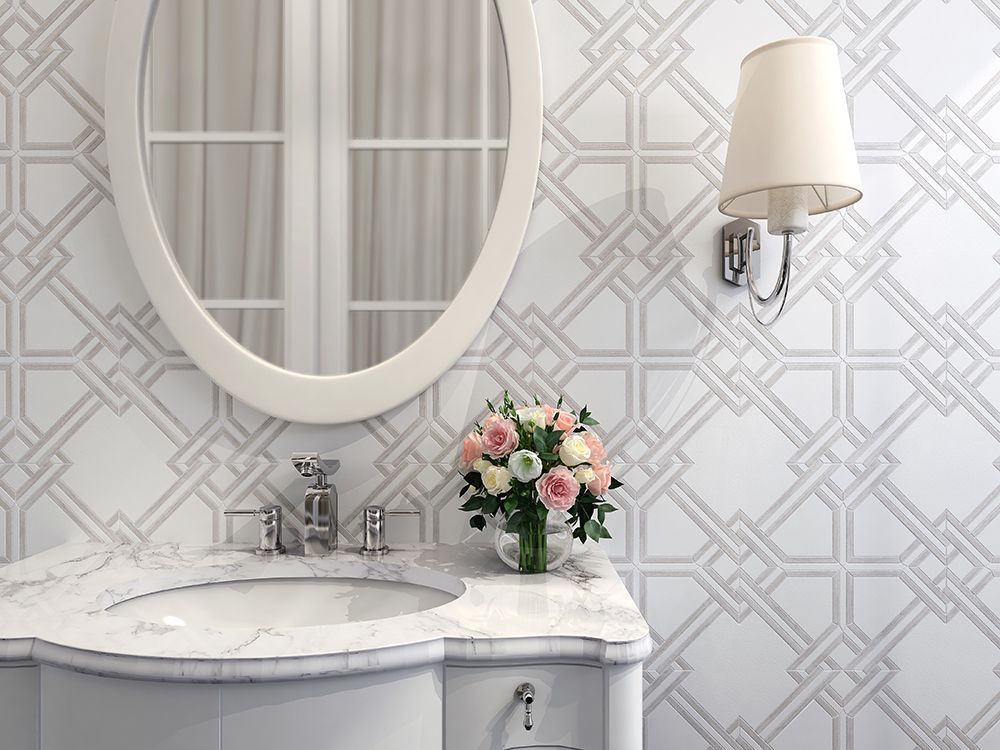Bathroom with oval mirror, floral arrangement, and patterned white and gray tile.