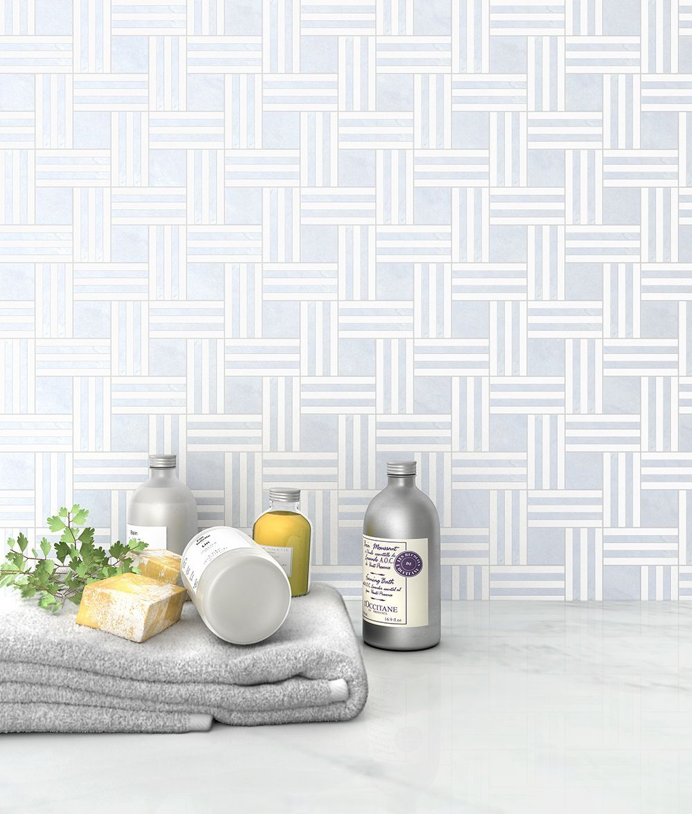 Bathroom scene with gray towel, soap, toiletries, and geometric light blue and white tile backsplash.