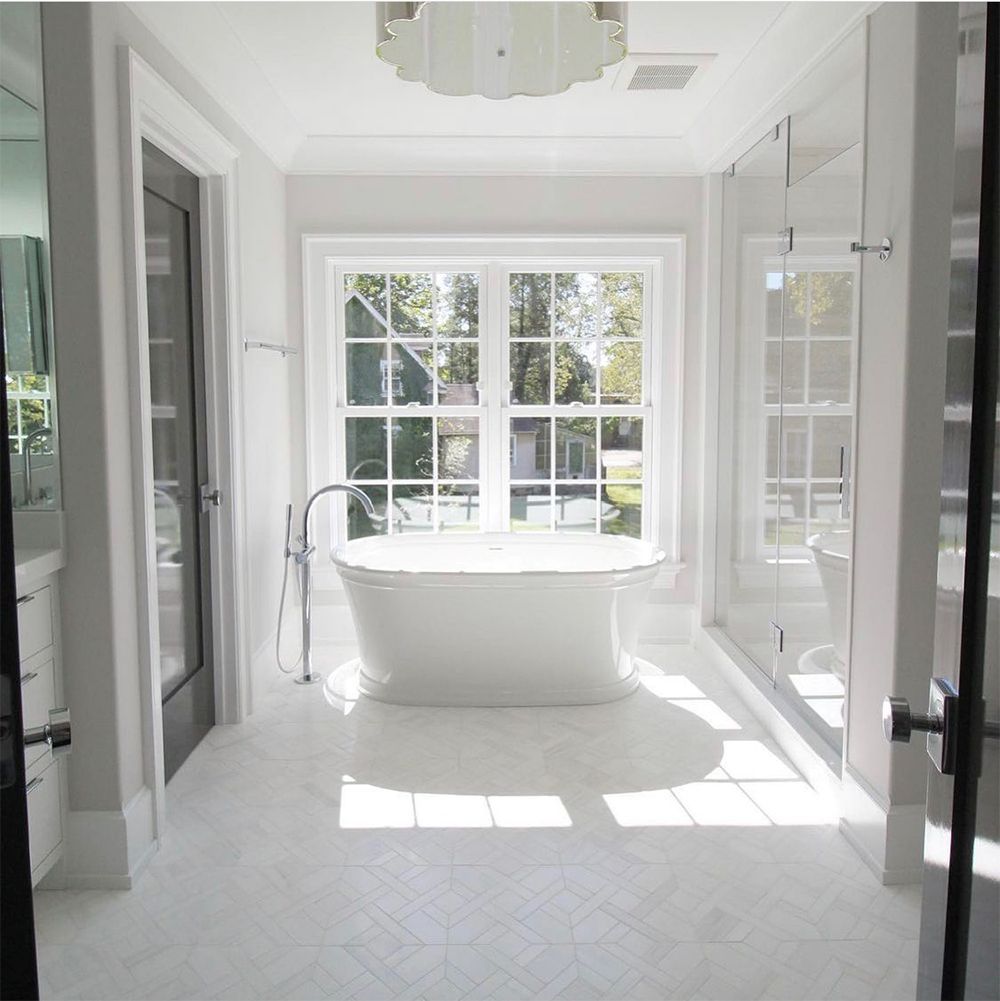 Bright white bathroom with a freestanding tub under a window.