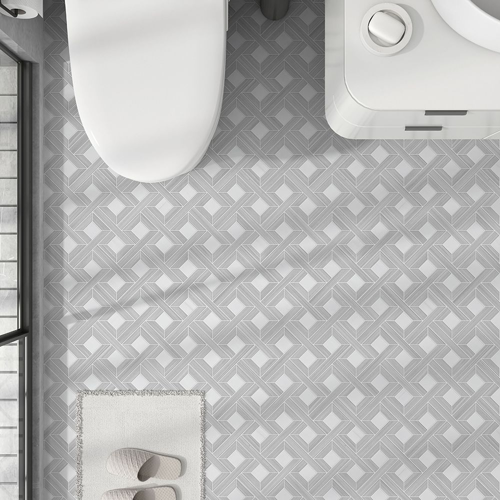 Overhead view of a bathroom with a patterned gray tile floor, toilet, washing machine, and small rug with slippers.