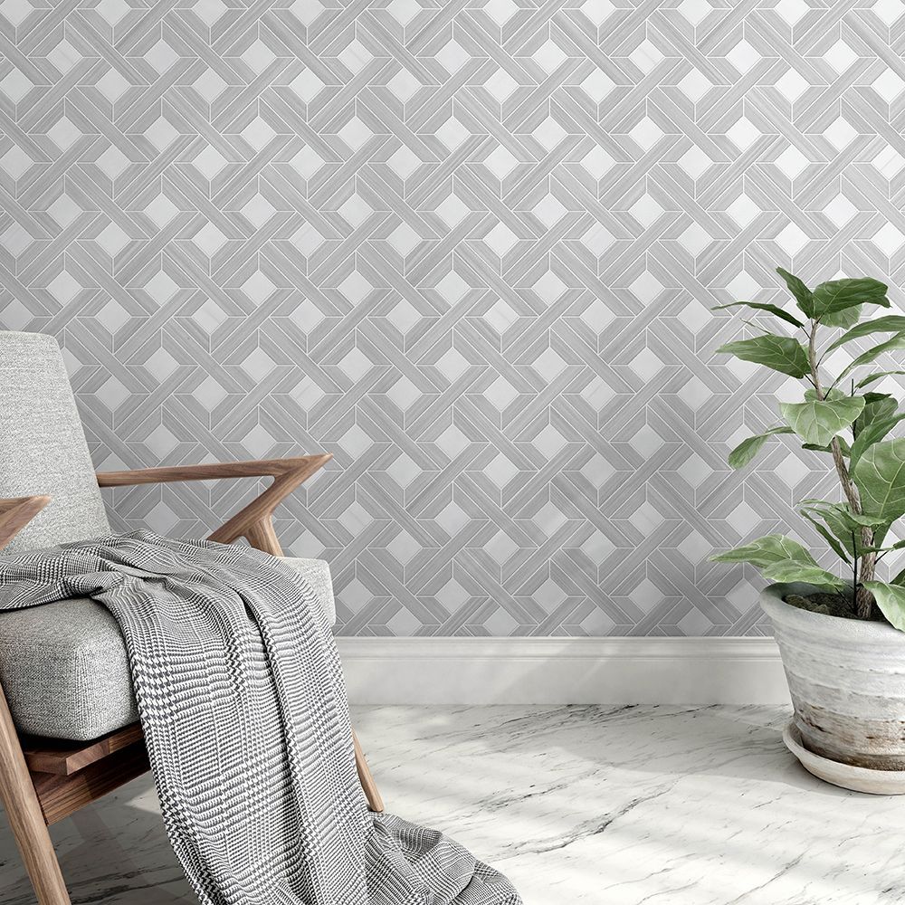 Gray patterned wall behind a wooden chair with a blanket and potted plant on a marble floor.
