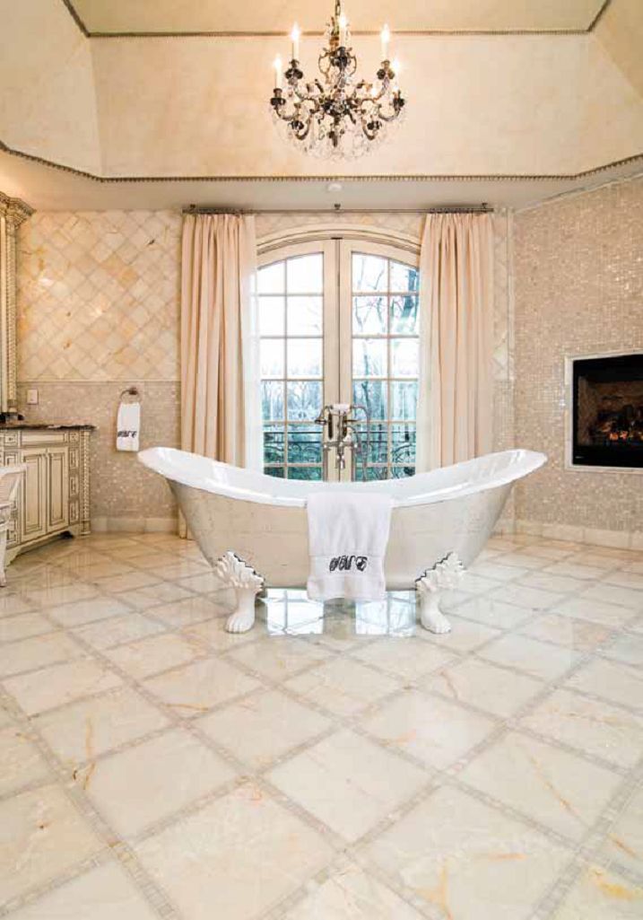 Elegant bathroom with a clawfoot tub, fireplace, chandelier, and patterned tile floor.