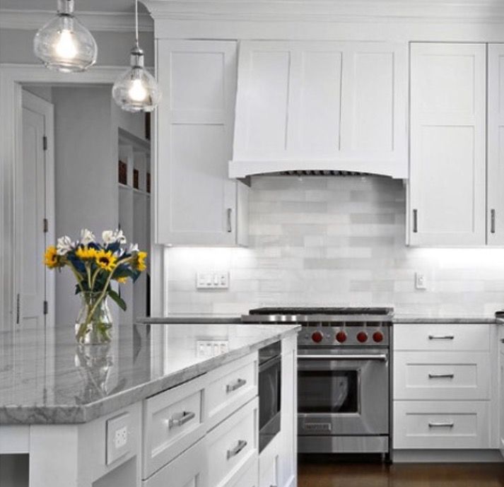 White kitchen with island, cabinets, range, and flower arrangement.