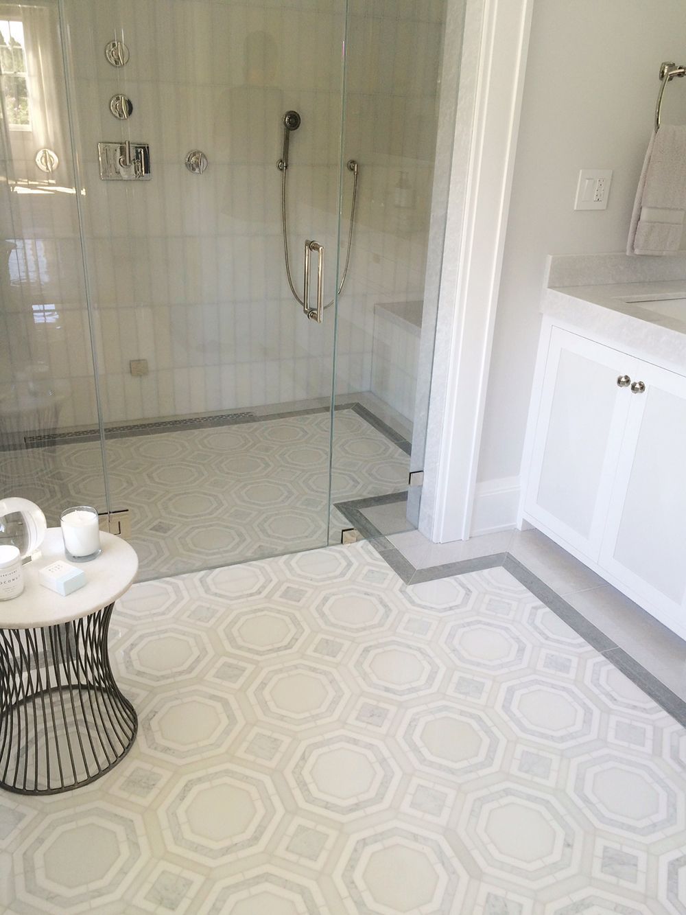 Bathroom with octagonal patterned tile floor, glass shower, and white vanity.