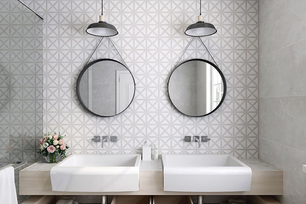 Bathroom with two round mirrors hanging over white sinks, patterned wall tile.