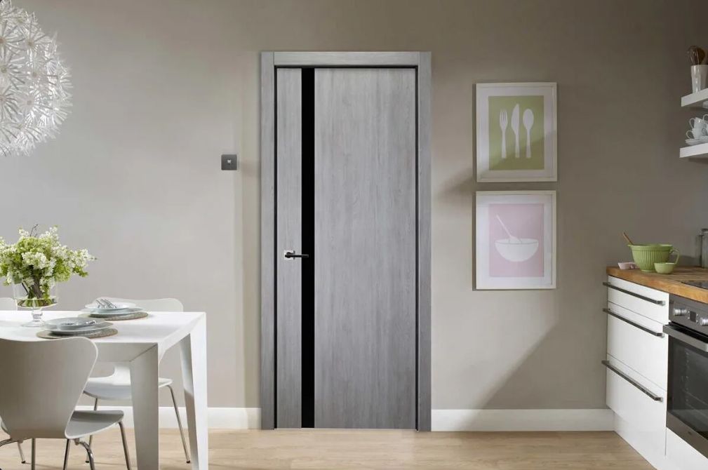 Interior door with black accent stripe; light gray walls, kitchen visible.