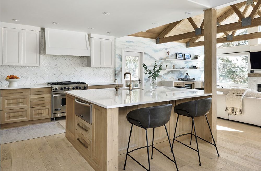 Modern kitchen with light wood cabinets, white countertops, and an island with stools.