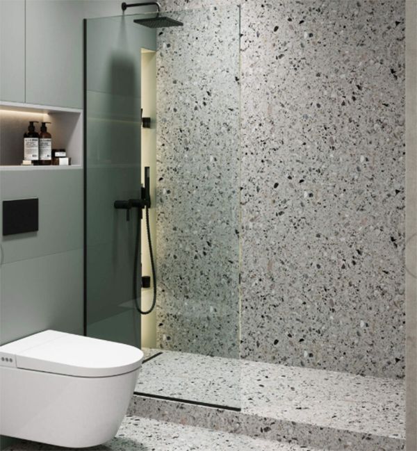 Bathroom with terrazzo tile walls and floor, black shower fixtures, and a white toilet.