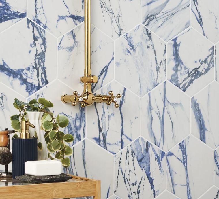 Hexagonal blue and white marble tile shower wall with gold fixtures.