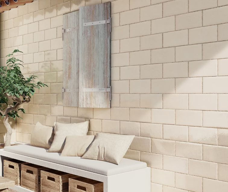 Bench with pillows and wooden crates, against a beige brick wall, with a weathered shutter and greenery.
