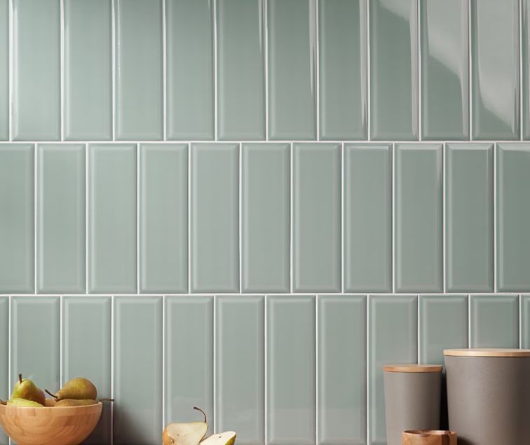 Green vertical subway tiles on a wall, with pears in a wooden bowl and gray containers.