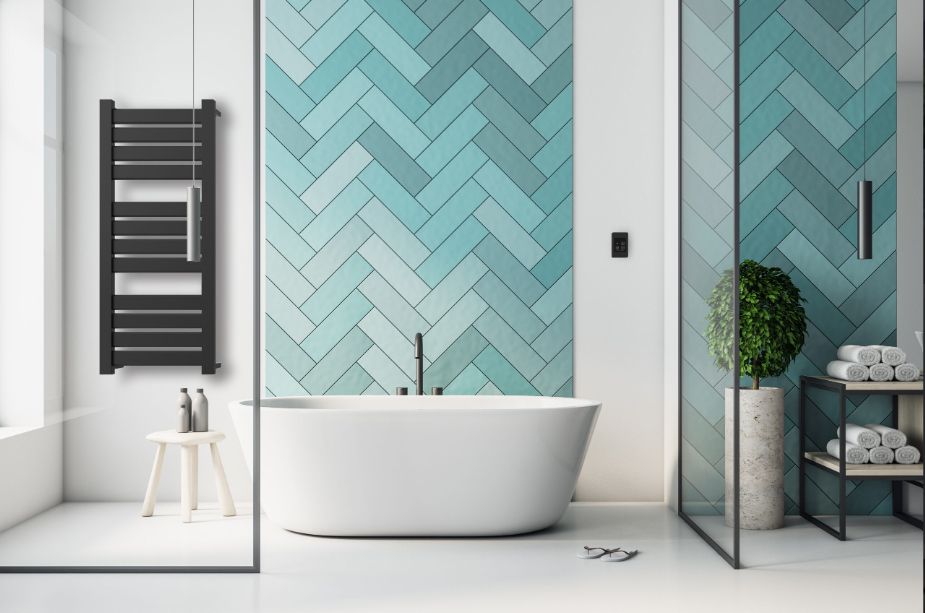 Modern bathroom with black towel warmer, white tub, and turquoise herringbone tile wall.