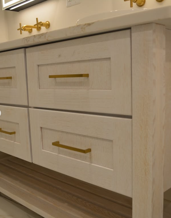 White bathroom vanity with gold hardware and two drawers.