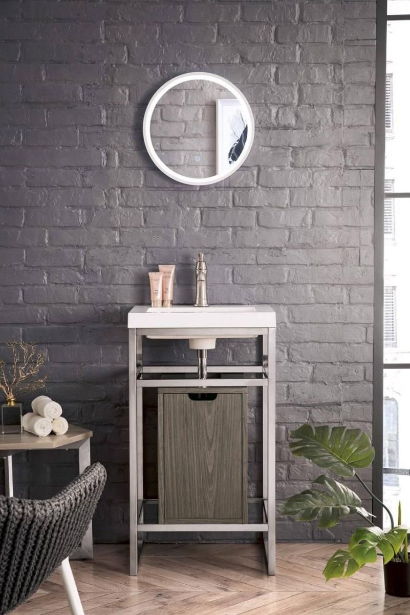 Bathroom vanity with sink, mirror, and decorative items against a brick wall.