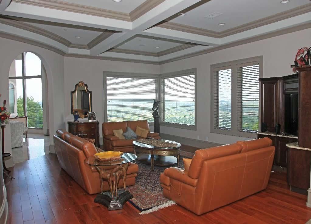 Living room with leather sofas, large windows, wood floors, and decorative ceiling.