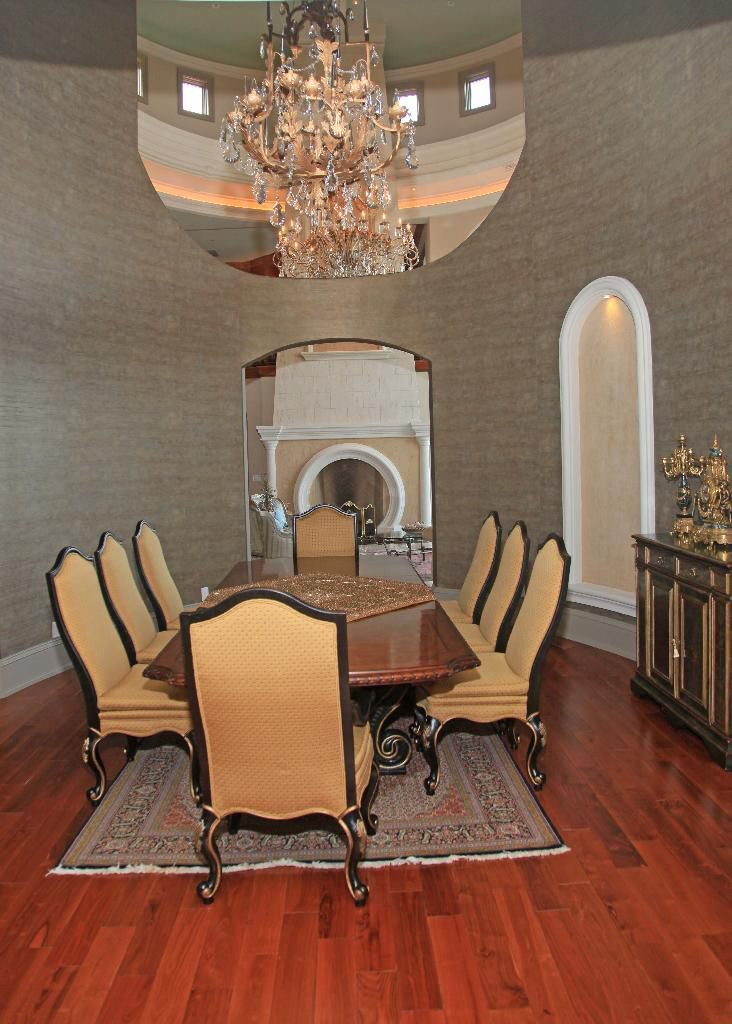 Elegant dining room with chandelier, table, and chairs; hardwood floor.