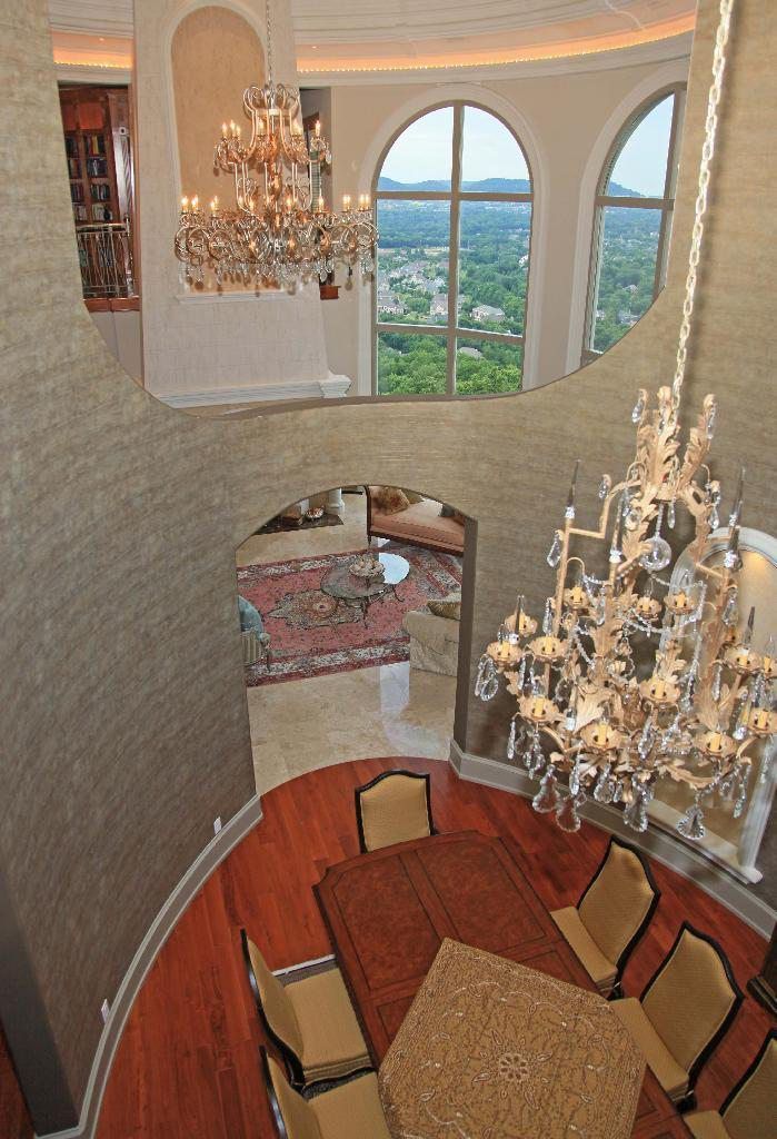 Luxurious dining room with chandelier, arched windows, and a view.
