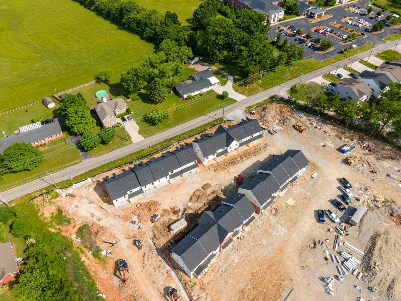Aerial view of new townhouses under construction; dirt and equipment visible.
